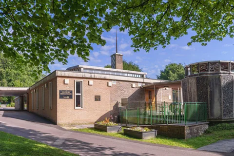 Salisbury Crematorium — a low brick building with a slender spire, seen from the drive beneath trees
